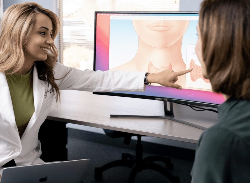 Dr. Linda Khoshaba showing a thyroid illustration on a computer screen to a patient